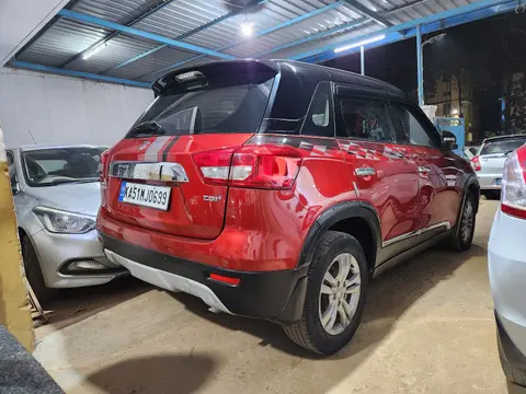 A red compact SUV under the shed roof, seen from behind, with other cars alongside.