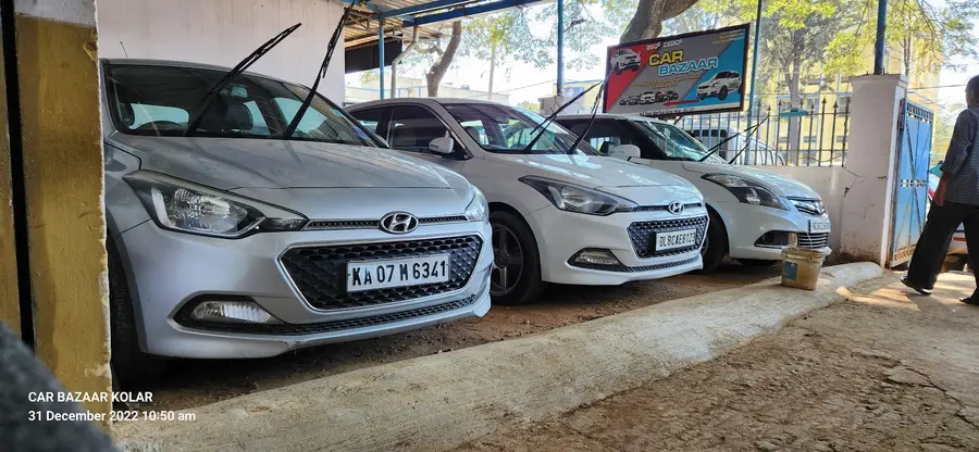 A row of white Hyundai i20 hatchbacks parked nose-out on the forecourt.